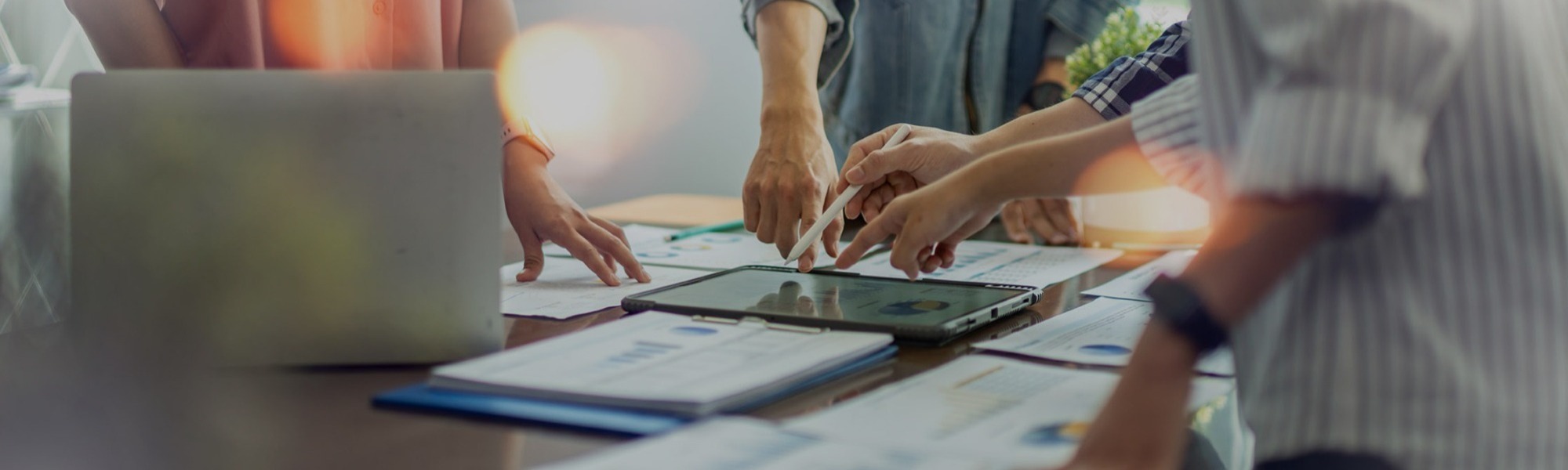Business team collaborating over tablets and documents at a meeting table