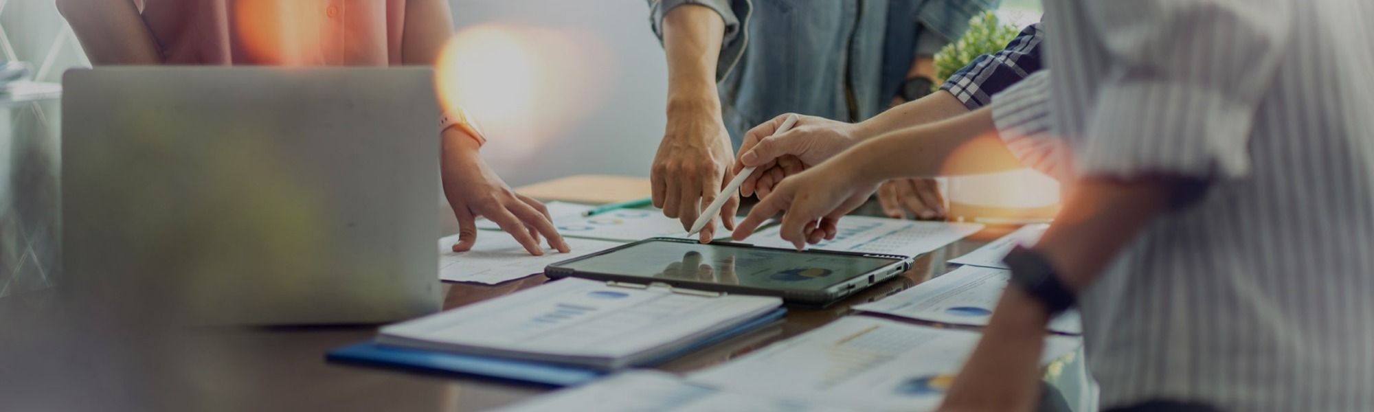 Business team collaborating over tablets and documents at a meeting table